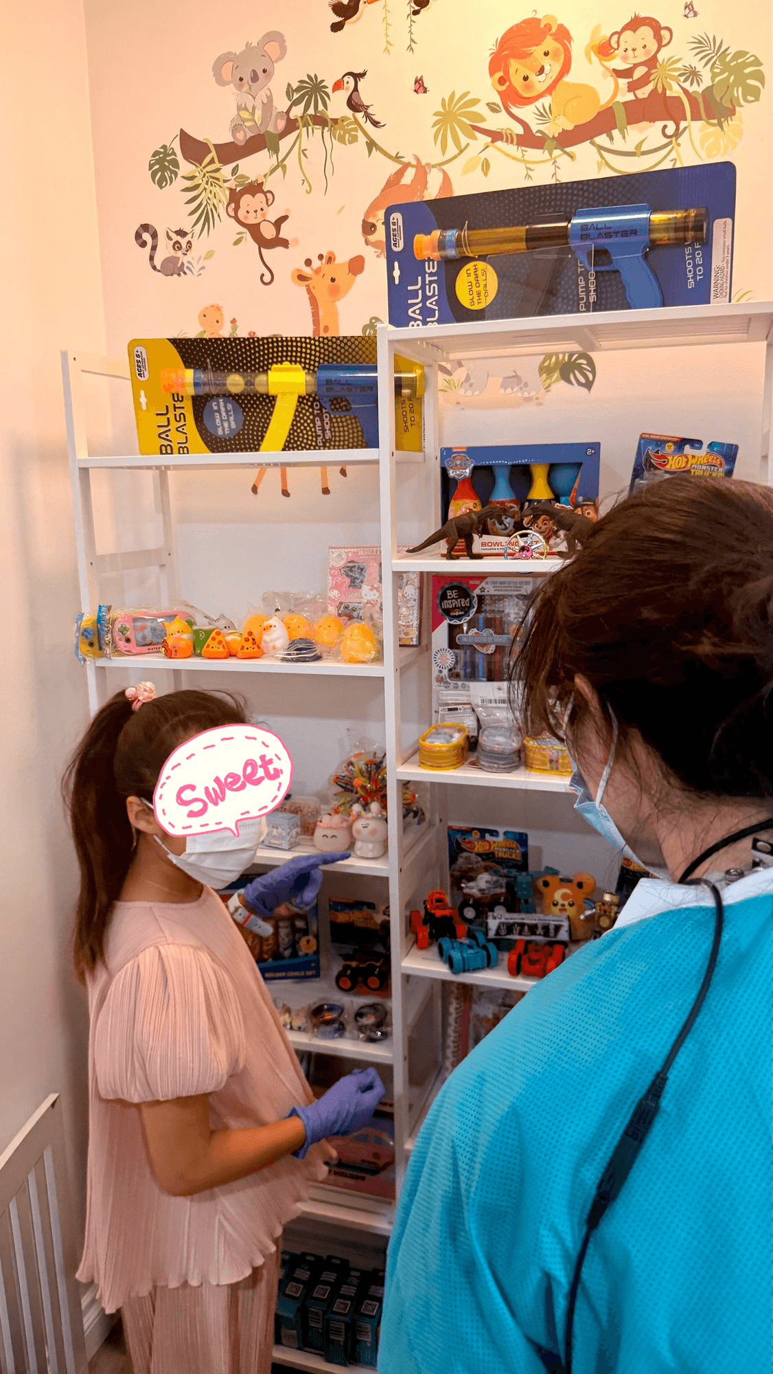 A young patient choosing a prize from the Kids Dental Story reward shelf